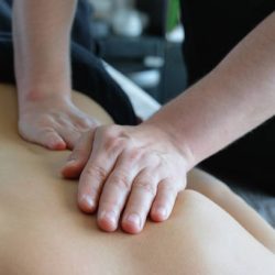 A doctor, a man, an osteopath, a rehabilitologist conducts physiological therapy with his hands. A masseur, a chiropractor does therapeutic massage to a patient, relieves muscle clamps and back pain. Osteopathy session. Alternative medicine. Health care.